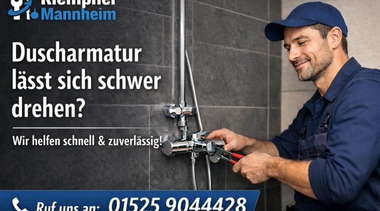 Klempner in blauer Arbeitskleidung repariert eine Duscharmatur im Bad – Klempner Mannheim